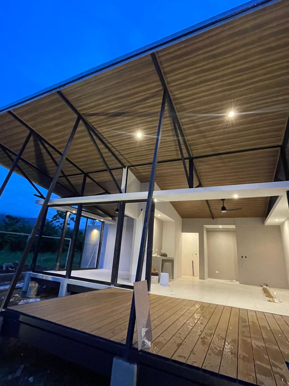 Construction progress — wood deck and sloped ceiling with black steel framing at the Ave de Fuego site, photographed at dusk