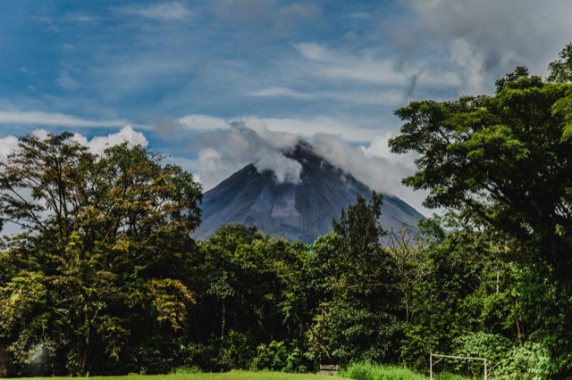 Arenal Volcano rising above the rainforest canopy with misty clouds